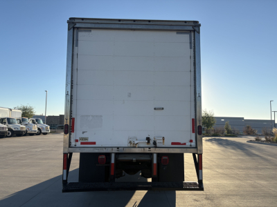 Box truck rear showing white cargo doors, bumper step, and tail lights with reflection.