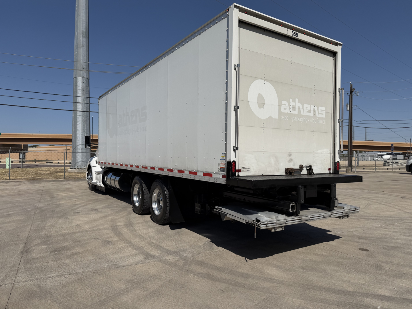 Kenworth T680 box truck with a large trailer in a parking lot, rear and left-side views visible.