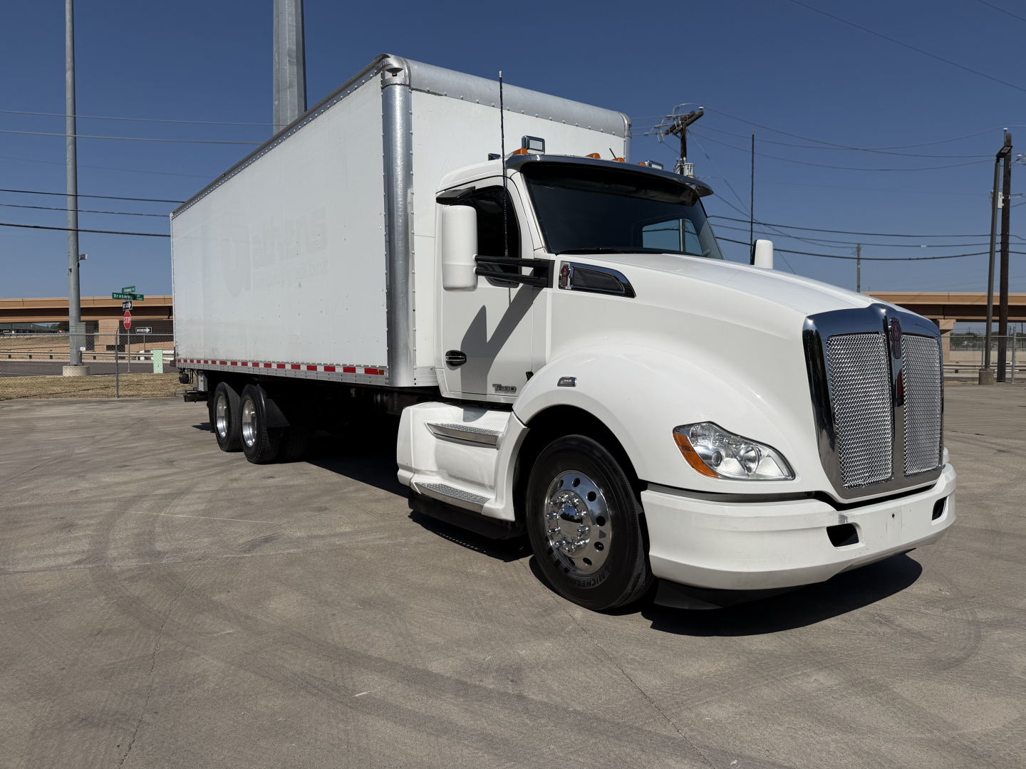 Kenworth T680 box truck with white cab and box, front-right view showing grille, headlights, side mirror, and cargo box.