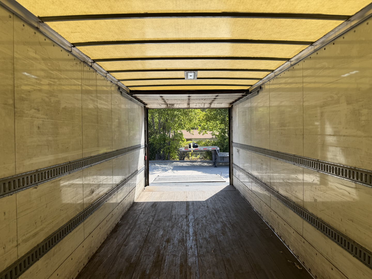 Kenworth T680 box truck interior view from trailer doorway showing loading area and exterior lot beyond.