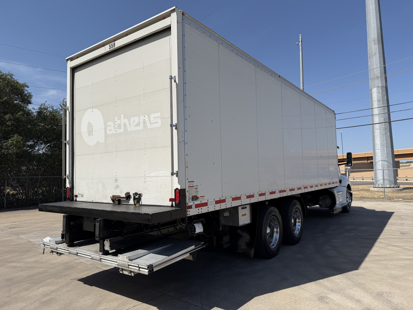 Kenworth T680 box truck rear and side view showing large white cargo trailer with stairs deployed at the back, box body, tandem rear axles, and Qathens logo on tail.