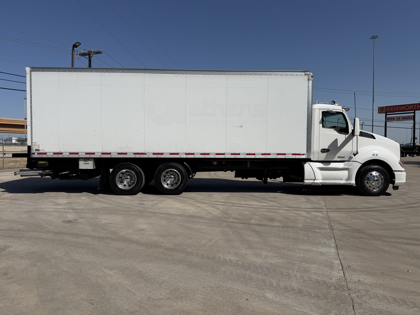 Kenworth T680 box truck side view showing cargo box and tractor cab with three rear axles.