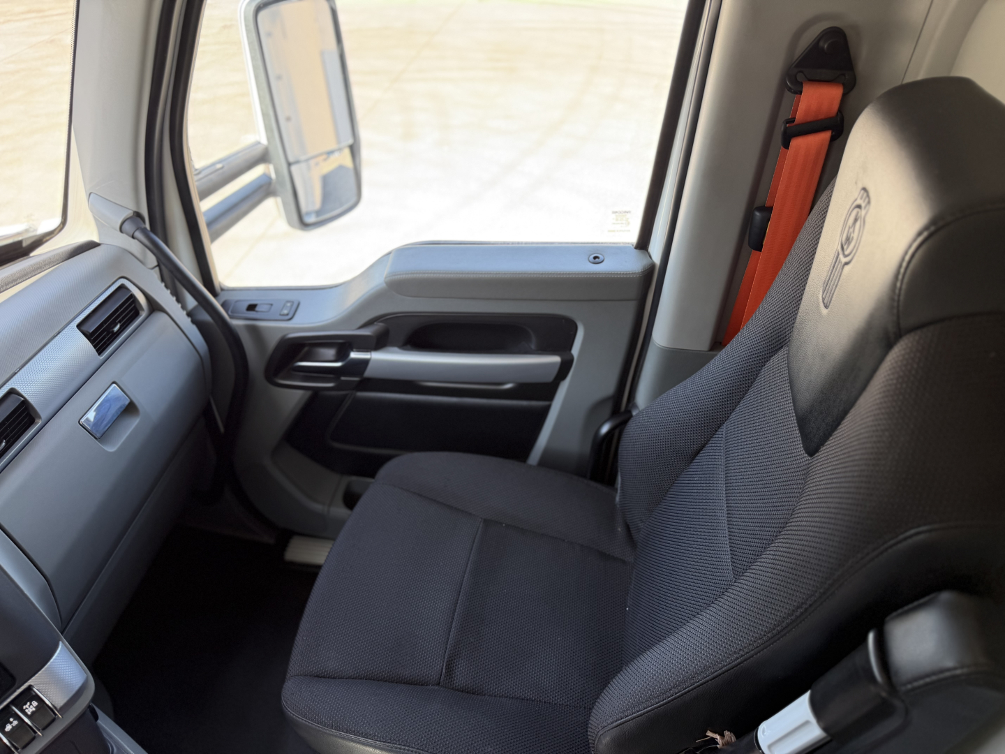 Kenworth T680 cab interior showing driver seat and door area with seat belt.
