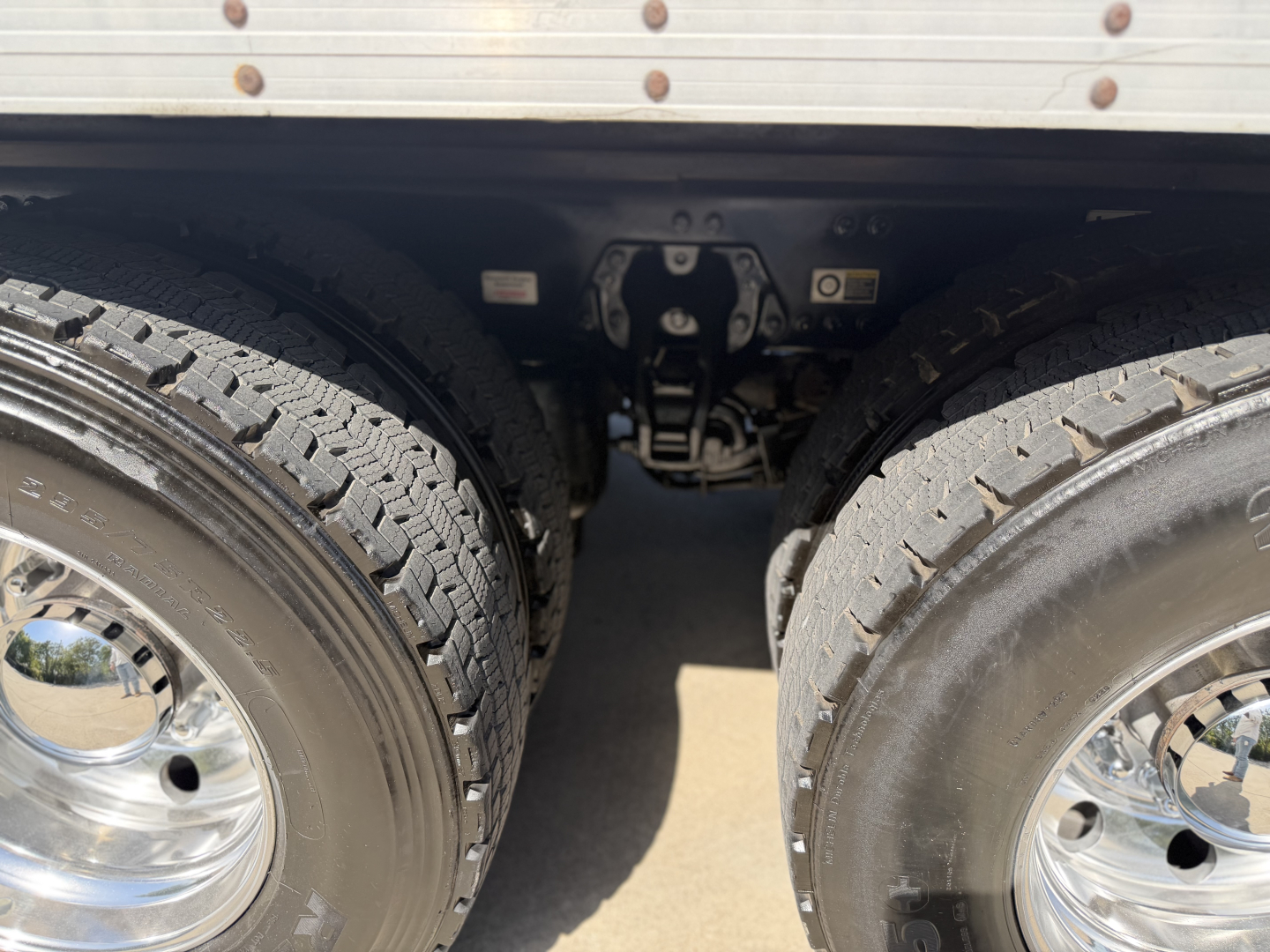 Kenworth T680 drivetrain area showing dual rear wheels and suspension undercarriage view with mud flaps and wheel hubs.