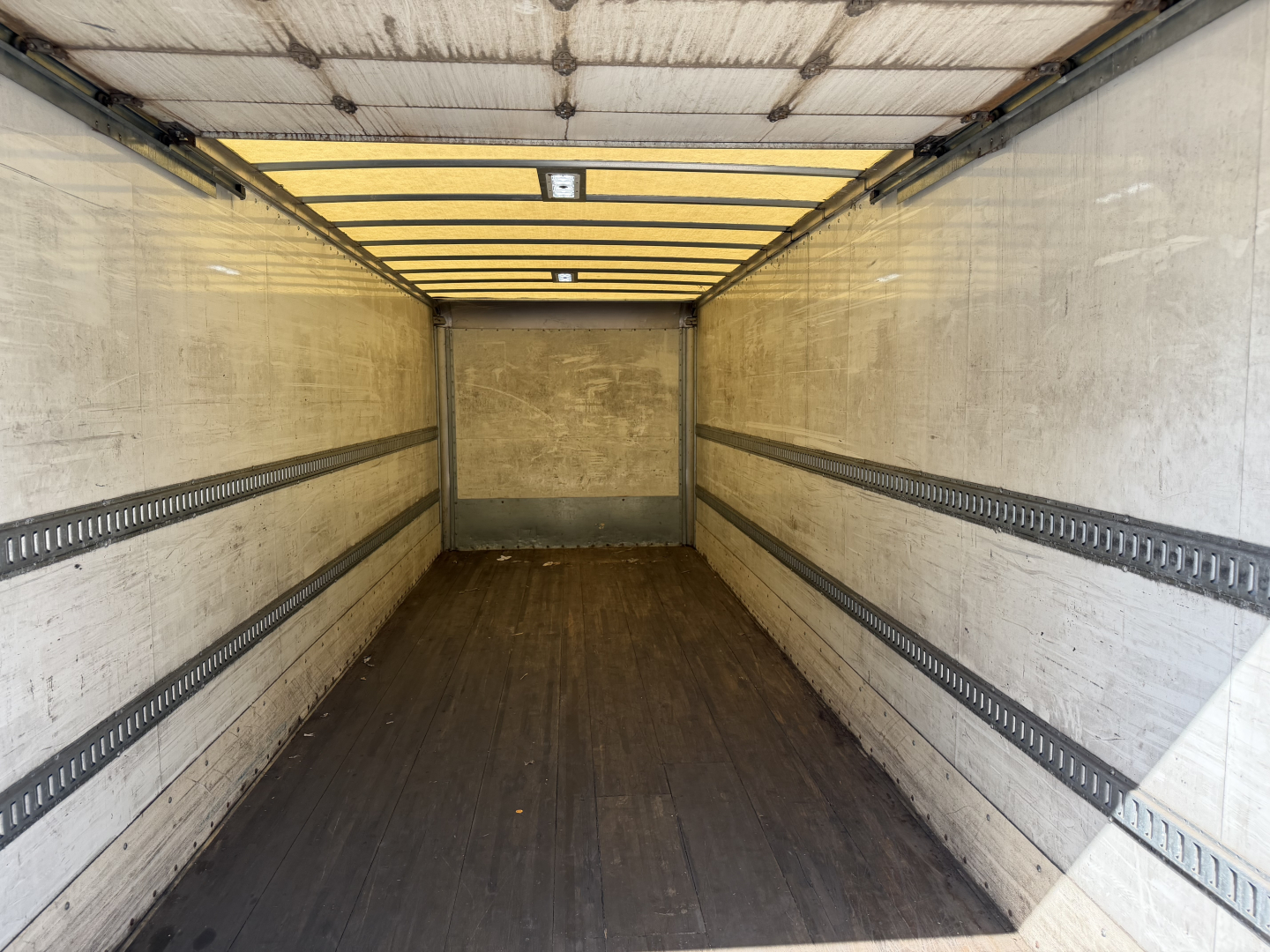 Kenworth T680 cargo box interior showing empty trailer with side E-track rails and wooden floor.