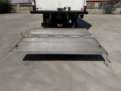 Back of a Kenworth T680 with a metal fold-down liftgate extending outward from the truck bed.
