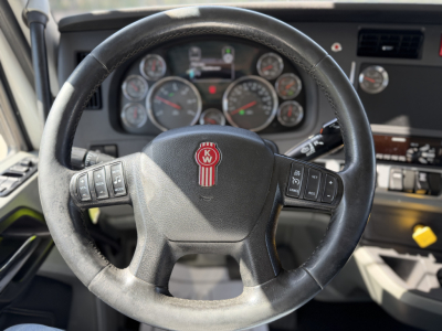 Kenworth T680 interior steering wheel and dashboard view showing instrument cluster, steering wheel with Kenworth emblem, and control buttons.