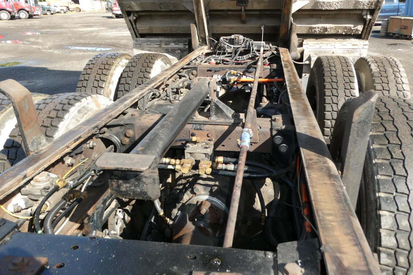 Truck chassis and rear drivetrain area of a 2006 Peterbilt 357 dump truck, showing the frame rails, rear axles, wiring, and hydraulic components with exposed undercarriage.