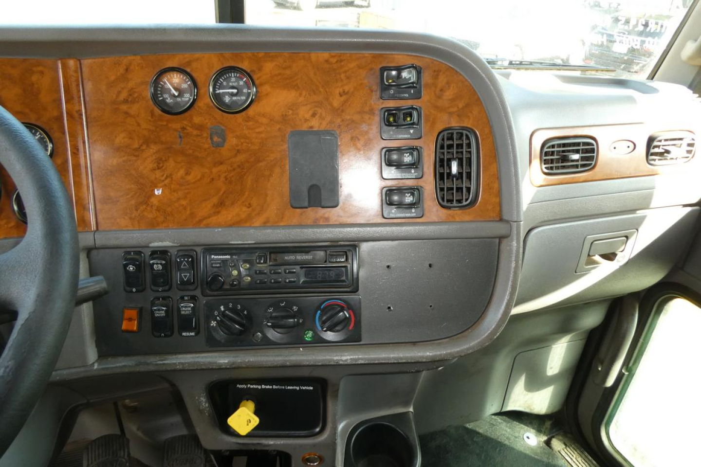 Peterbilt 357 dash and instrument cluster area showing woodgrain panel, gauges, switches, and climate controls.
