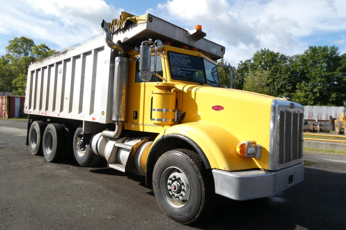 Peterbilt 357 dump truck in yellow with silver dump bed, side view showing front grille, cab, and dual rear axles.