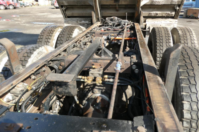 Truck chassis and rear drivetrain area of a 2006 Peterbilt 357 dump truck, showing the frame rails, rear axles, wiring, and hydraulic components with exposed undercarriage.