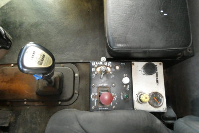 Peterbilt 357 cab interior showing shifter with gear indicator, control panel with red emergency stop button, gauges, and seat edge.