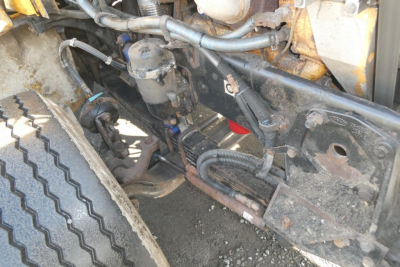 Peterbilt 357 engine bay with visible hoses, components, and frame; hydraulic lines and electrical harnesses near front wheel.