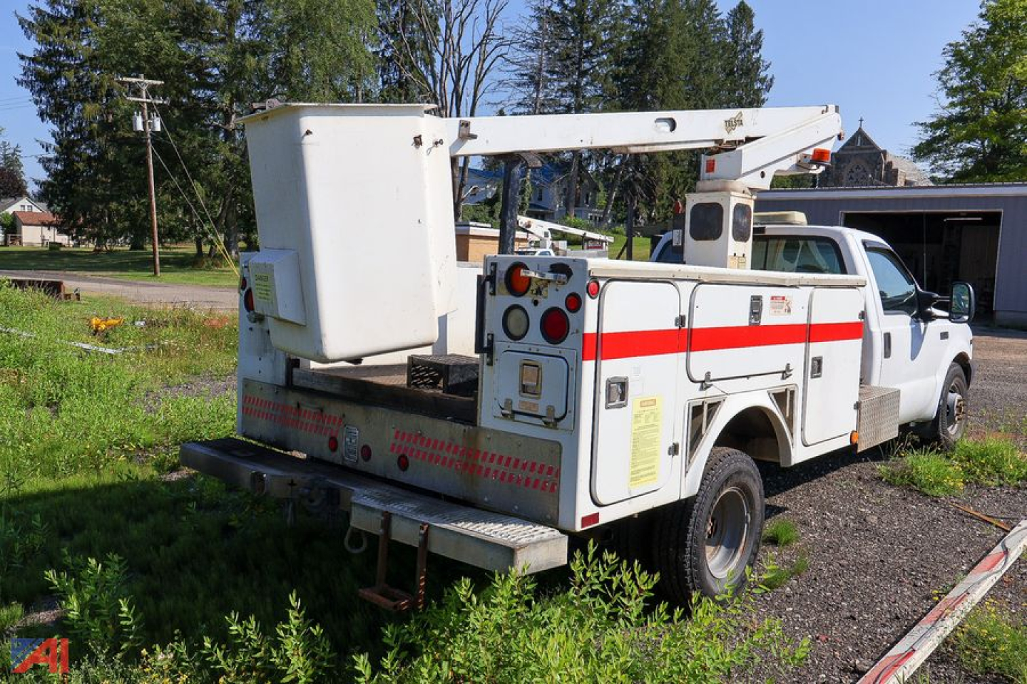 1999 Ford F-350 Super Duty Telsta bucket truck rear view showing bucket lift and utility body with red stripe.