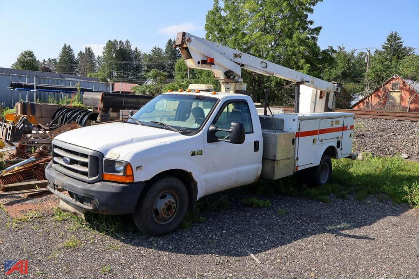 Ford F-350 bucket truck with Telsta aerial lift on a service body, white cab and utility compartments, on a gravel lot.