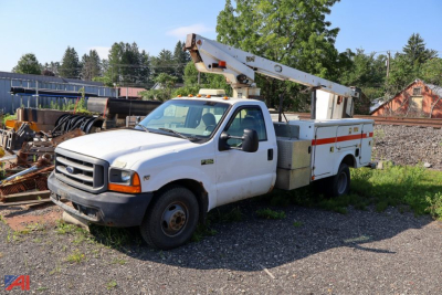 Ford F-350 bucket truck with Telsta aerial lift on a service body, white cab and utility compartments, on a gravel lot.