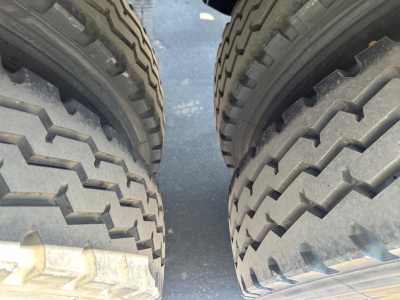 Two large truck tires side-by-side with tread pattern visible, part of a jet-side-dump trailer undercarriage view.