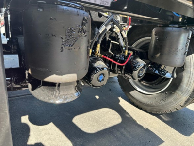 Jet side dump trailer undercarriage with hydraulic tanks, hoses, and wheel assemblies visible.