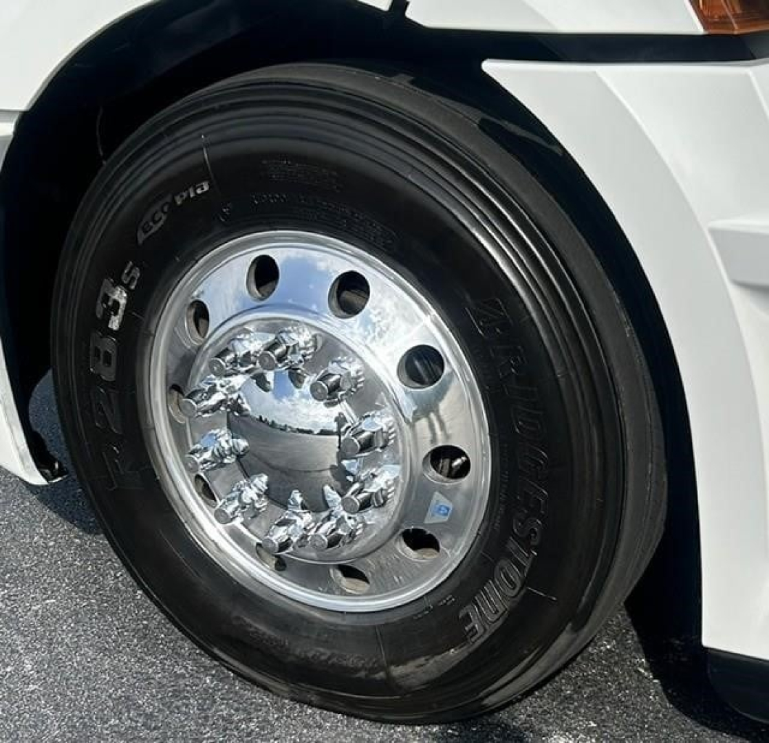 Front wheel of a Freightliner Cascadia 126 truck showing a chrome hubcap and tire with visible lettering.