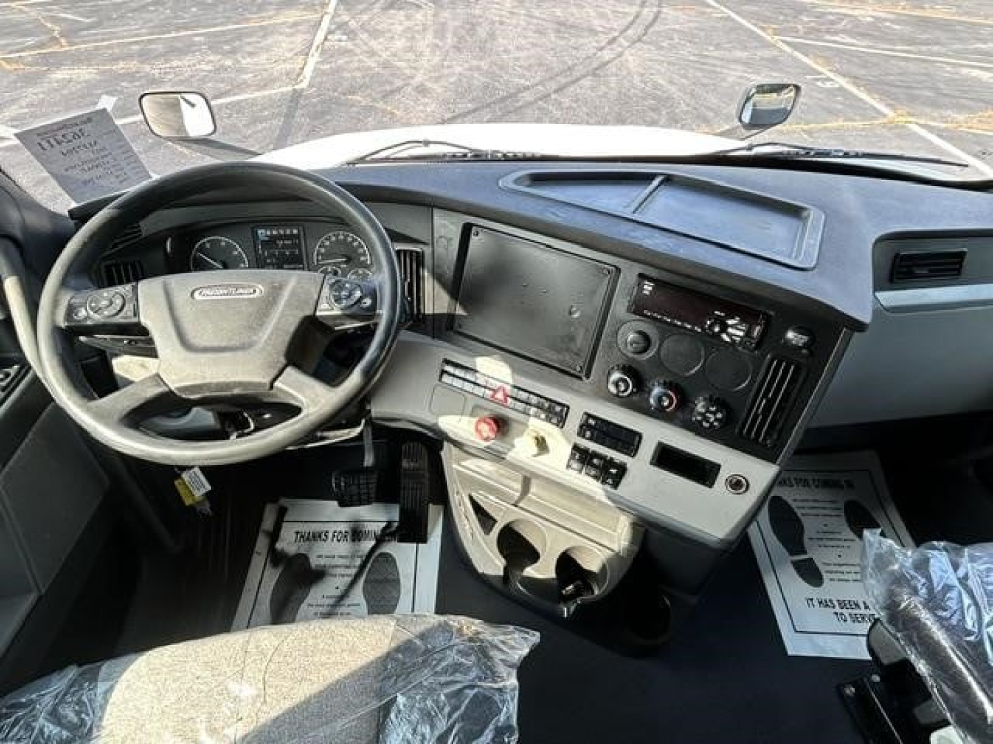 Freightliner Cascadia 126 interior dashboard and steering wheel with large touchscreen display, multiple controls, and cup holders visible.