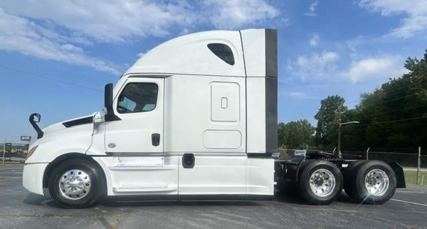 Freightliner Cascadia 126 tractor cab side view showing sleeper cab, white exterior, dual rear axles, chrome wheels, and aerodynamic design.