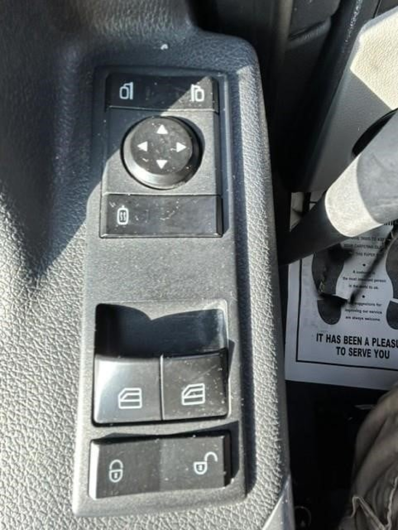 Truck window/door control panel showing window switch buttons and lock controls inside a Freightliner Cascadia cabin.