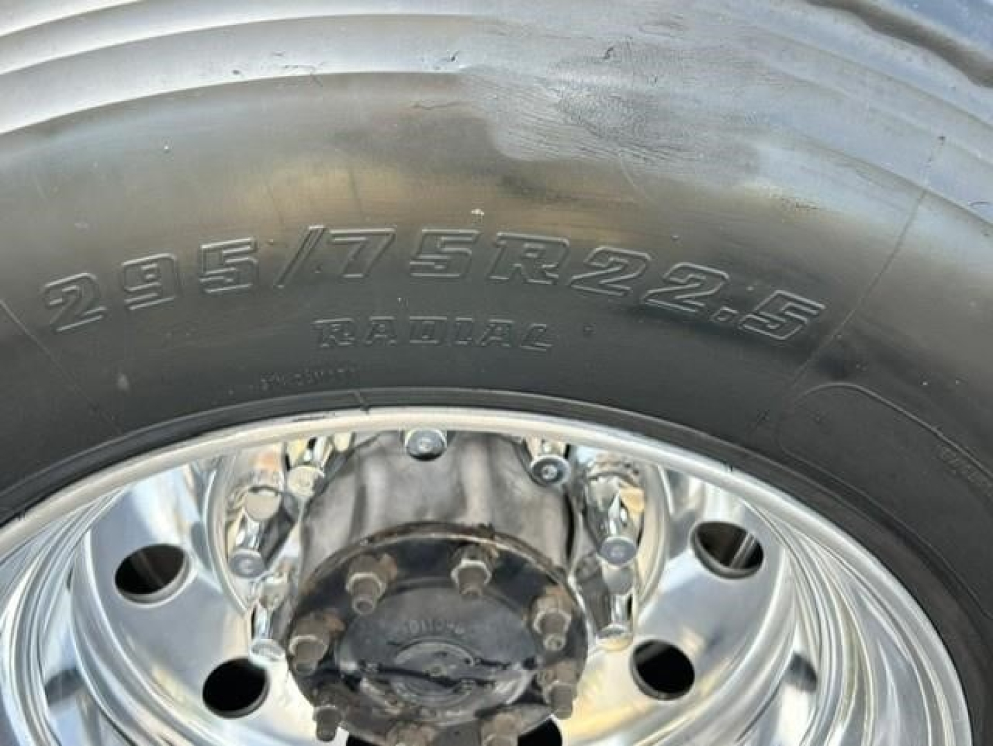 Front wheel with tire showing radial 295/75R22.5 and chrome hub showing lug nuts.