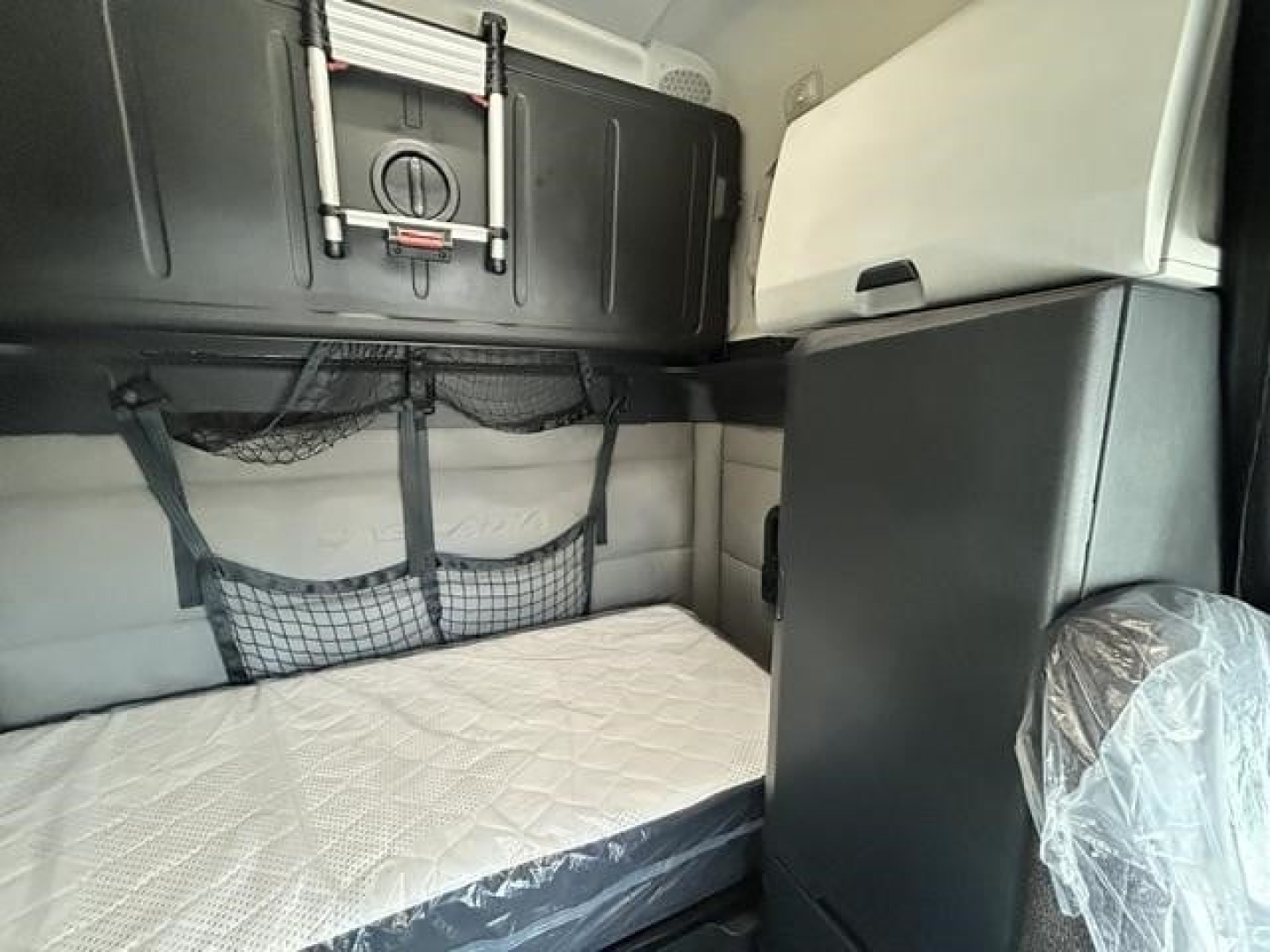 Freightliner Cascadia sleeper cab interior showing bunk bed and storage cabinets.