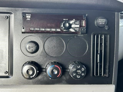 Dashboard panel with car stereo/head unit and climate controls. Visible text includes 'POWER OUTLET' on a circular cap, and parts of the stereo display and buttons.