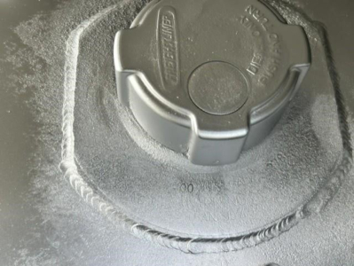 Cap on fluid reservoir in engine bay showing text and circular cap