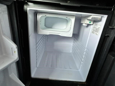 Freightliner Cascadia engine bay showing compact auxiliary cooler or starter area? image appears to show a small front storage compartment or auxiliary unit in a recessed bay with a white interior and label on right side.