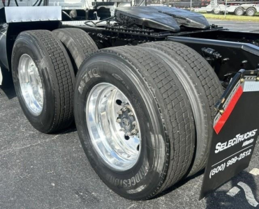 Dual rear axle on a Freightliner Cascadia truck showing heavy-duty tires and chrome rims; part of the chassis and fifth-wheel deck visible.