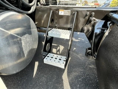 Freightliner Cascadia 126 engine bay area showing steps and frame, with fuel tank on left and step plate in center.