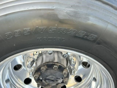 Front wheel with tire showing radial 295/75R22.5 and chrome hub showing lug nuts.