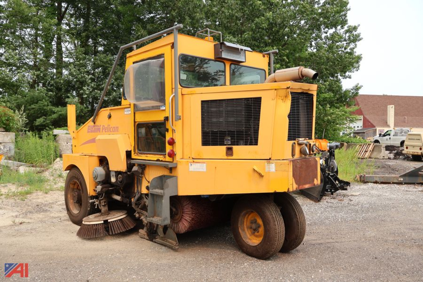 2006 Elgin Pelican Sweeper truck in field with yellow cab, large brushes underneath, rear exhaust and hopper visible.