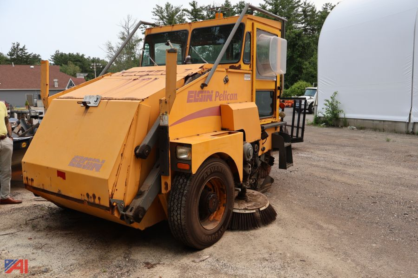 Elgin Pelican sweeper truck in yellow, side view showing large front sweeper housing and cab with Elgin Pelican branding.