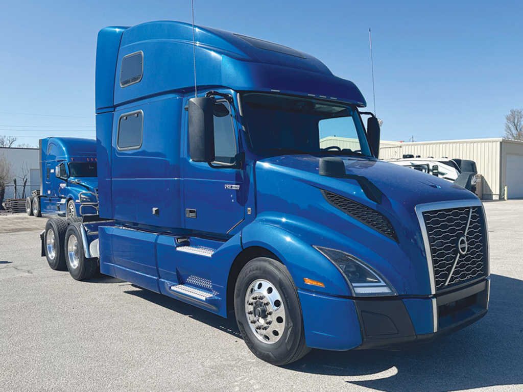Volvo VNL 860 sleeper cab truck in blue, front three-quarter view showing grille, headlights, and side mirrors.
