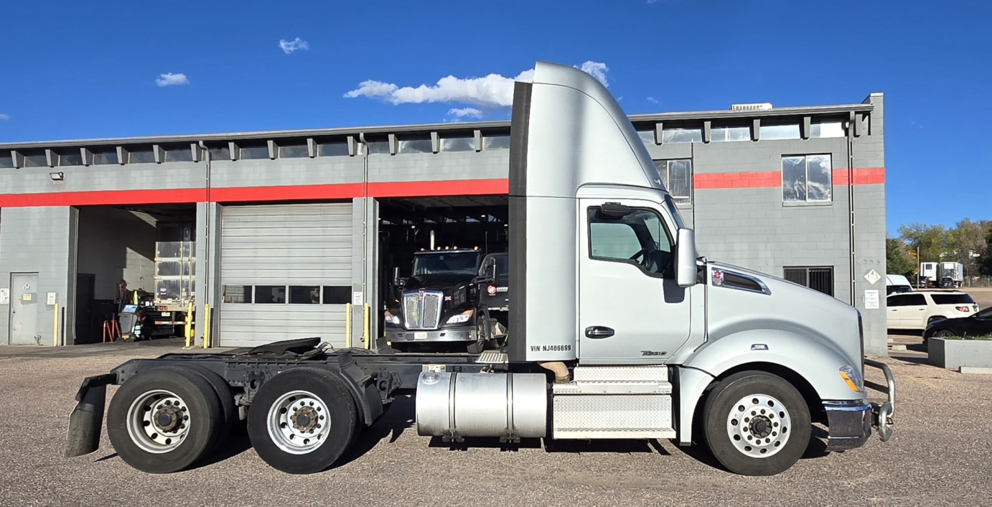 Kenworth T680 tractor in side view showing cab logo and chassis with dual rear axles and fuel tanks.