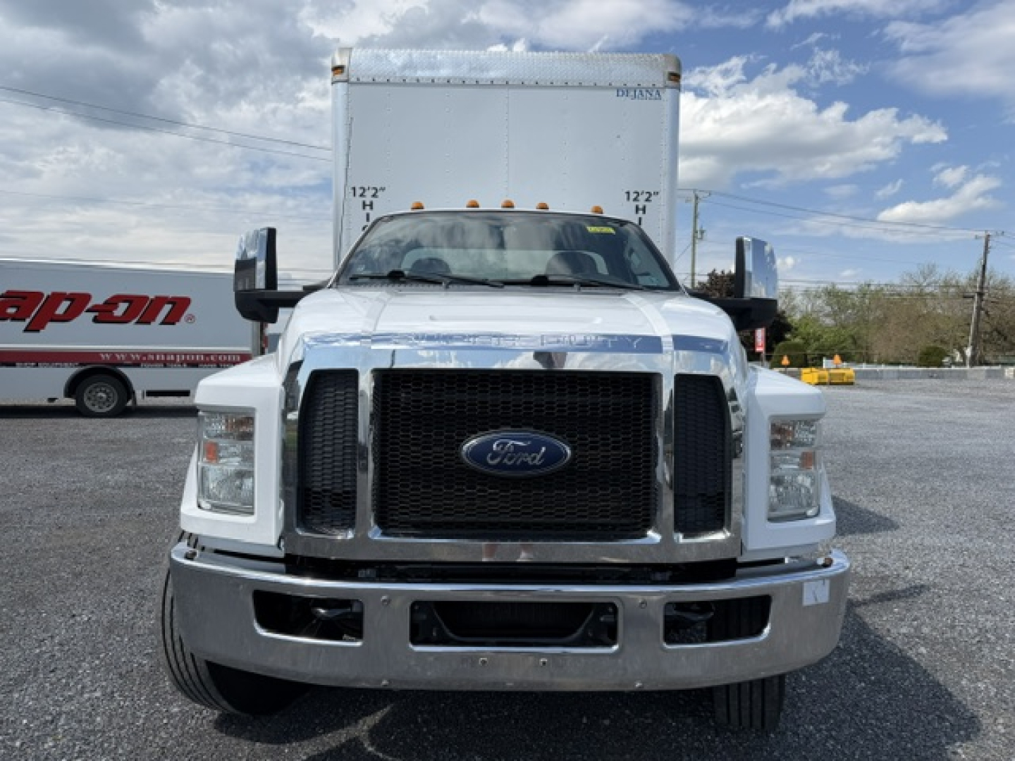 Front view of a white 2016 Ford F-750SD box truck with large black grille, bumper chrome, dual side mirrors, and box body behind cab.