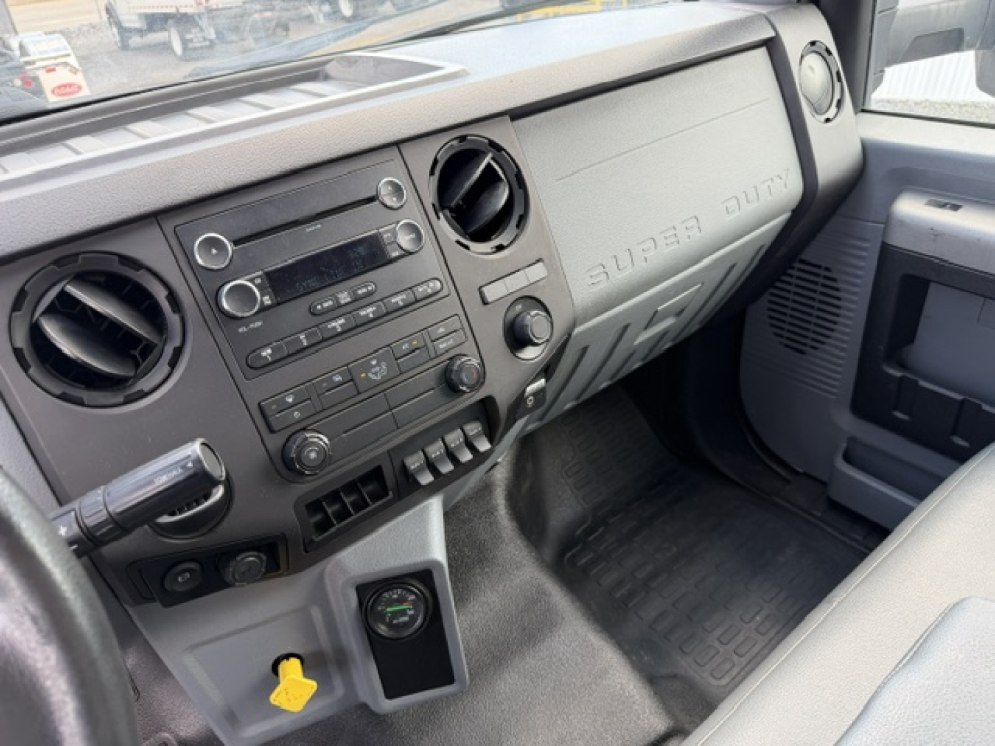 Ford F-750SD truck interior dashboard view showing center console with radio, climate controls, air vents, ignition, and steering column; embossed dash label reads 'SUPER DUTY'