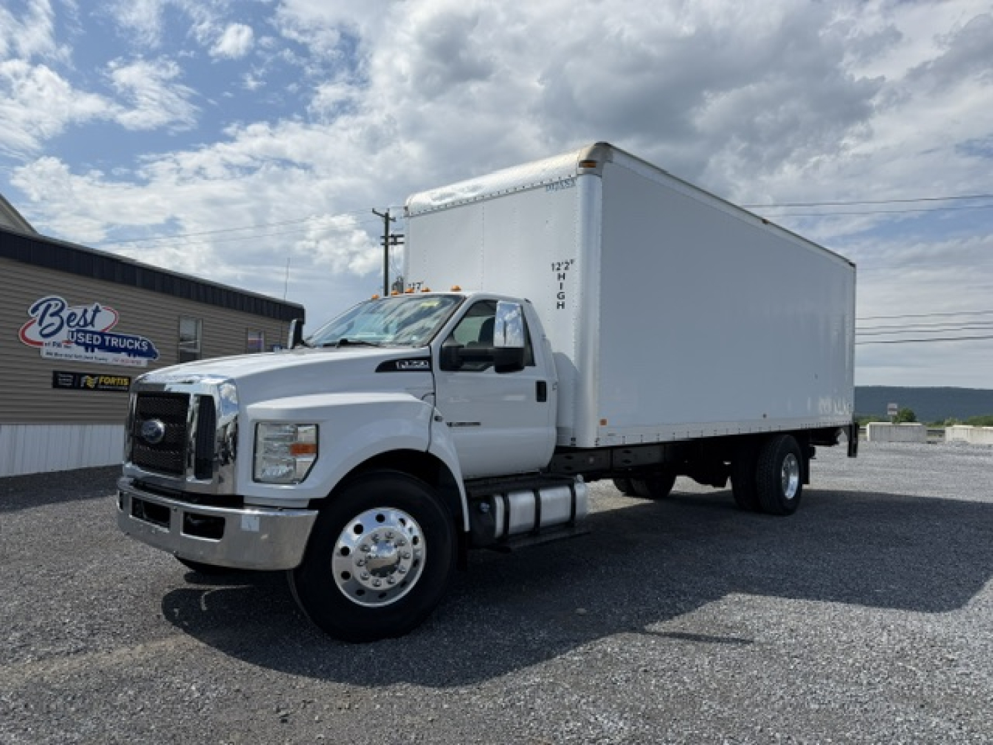 Ford F-750SD box truck with cargo box, front cab and large white box body. Side view shows cab, wheel, and fuel tanks. No visible text legible on sides other than general truck shape.