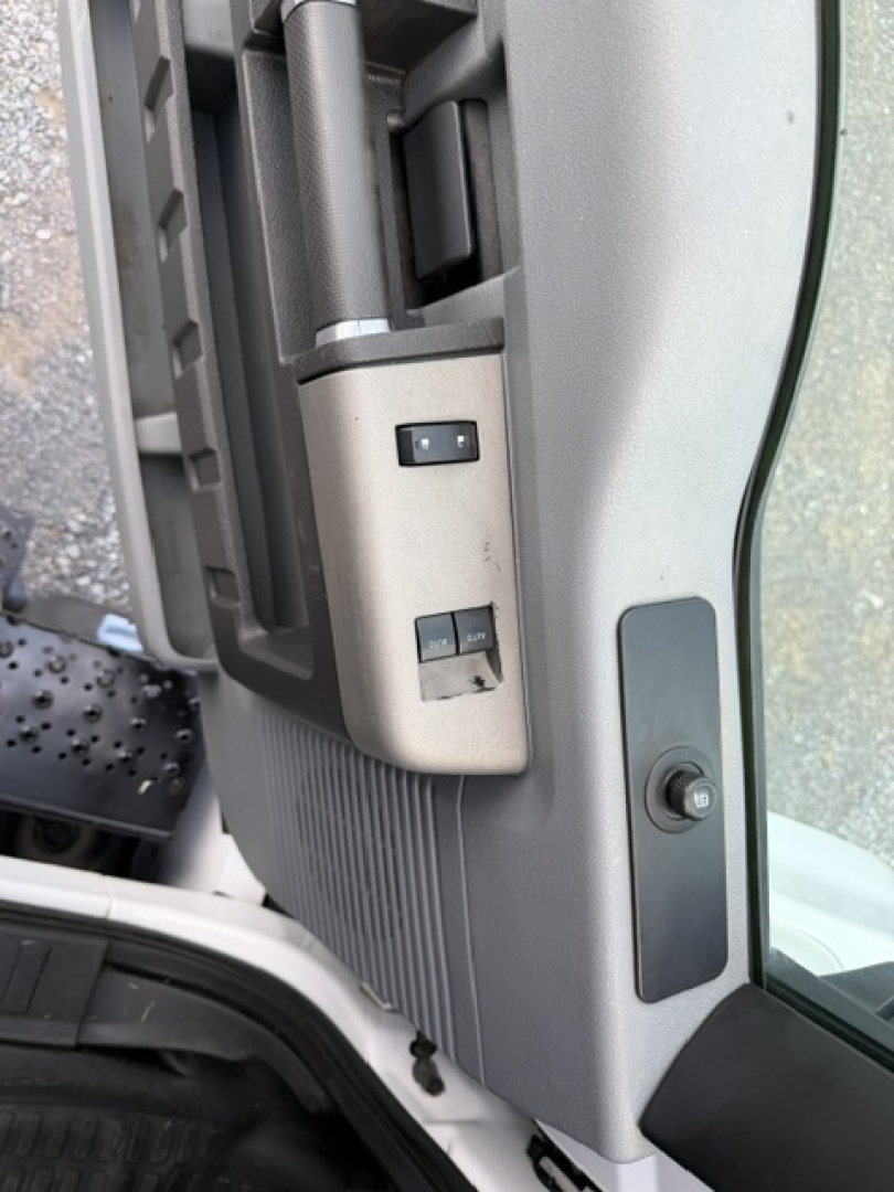 Cab interior: switches and door panel on Ford F-750SD truck showing window/lock switches and seam near door frame.