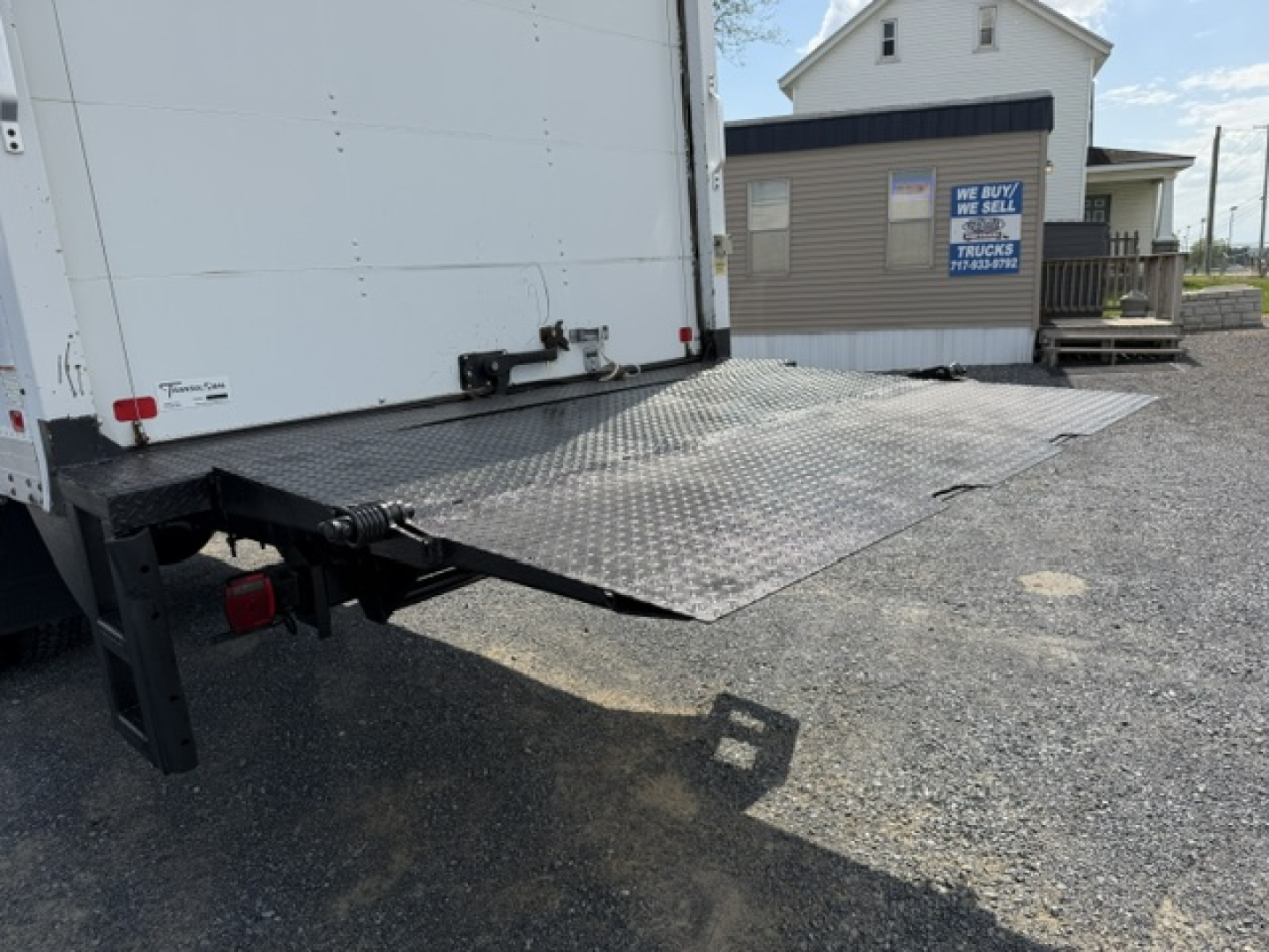 Truck bed ramp and rear of a 2016 Ford F-750SD box truck showing aluminum loading ramp and bumper area.