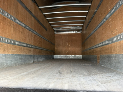 Truck cargo area of a 2016 Ford F-750SD box truck showing empty wooden side walls and metal rails.