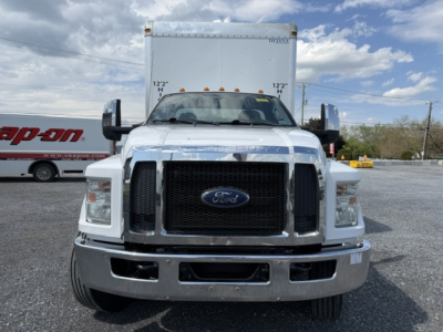 Front view of a white 2016 Ford F-750SD box truck with large black grille, bumper chrome, dual side mirrors, and box body behind cab.