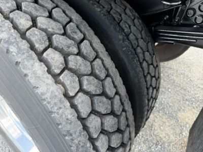 Truck wheel/tire assembly showing tread pattern and dual rear tires under a box truck chassis.