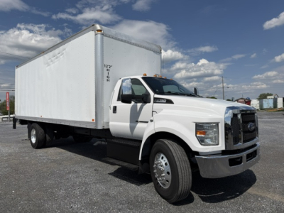 Box truck with a large white box body attached to a Ford F-750SD chassis, 6-wheel arrangement, front view at an outdoor lot.