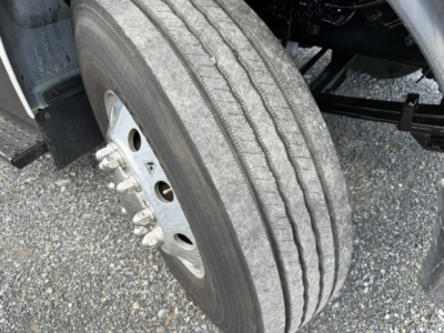 Ford F-750SD front wheel and dual rear tires, metal wheel with lug nuts and tire tread visible.