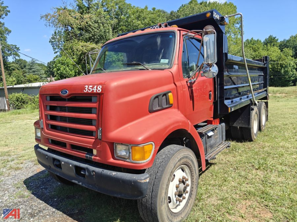 Ford Louisville 8500 dump truck in red with black dump bed, front grille, and number 3548 visible; side view on grassy lot.
