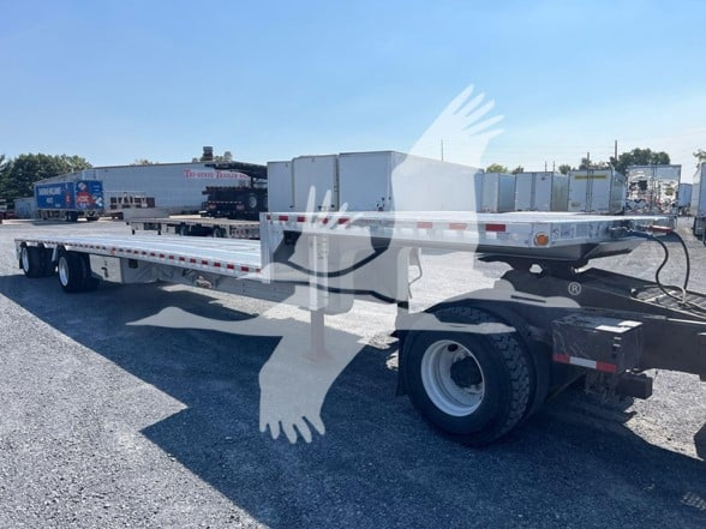 Dropdeck trailer with flatbed and central toolbox, rear wheels visible, side rails and drop mechanism. CDL? 2019 Reitnouer Dropmiser listing with stock 7529 in background.